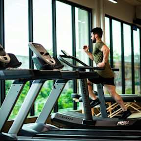 A man is running on a treadmill in a gym.