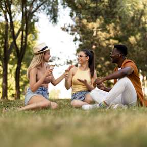 Three friends sitting on the grass in a park.