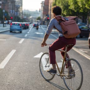 a man riding a bike down a city street with a backpack on