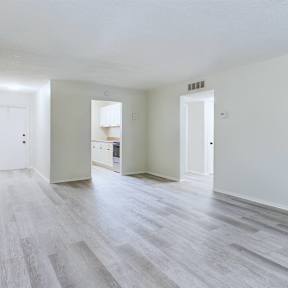 A spacious room with wooden flooring and white walls.