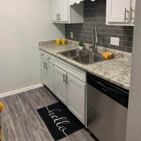 a kitchen with white cabinets and a stainless steel sink