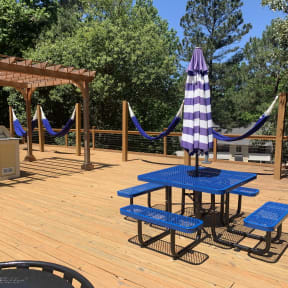 a picnic table with an umbrella and benches on a deck