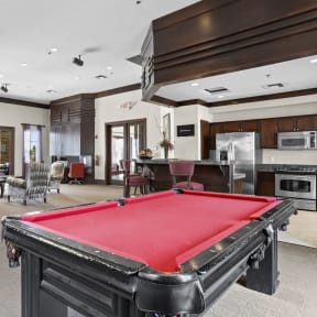 a red pool table in a living room with a kitchen