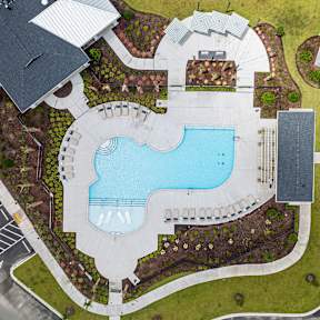 A large swimming pool surrounded by a grassy area and a building in the background.