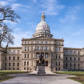 A large, grand building with a dome and a statue in front.