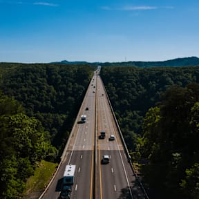 A highway with multiple lanes of traffic surrounded by dense greenery.