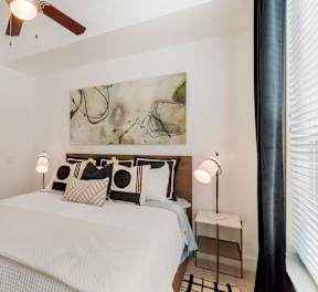 A bedroom with a large bed and a ceiling fan.