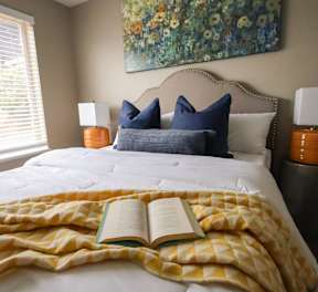 A bedroom with a bed, chair, and a ceiling fan.