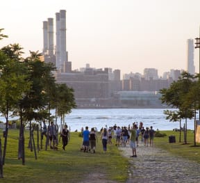 people walking on a path near the water with a city in the background at 34 Berry, Brooklyn, NY