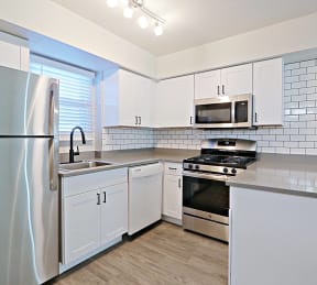 an empty kitchen with white cabinets and stainless steel appliances at Allora Phoenix Apartments, Phoenix, Arizona