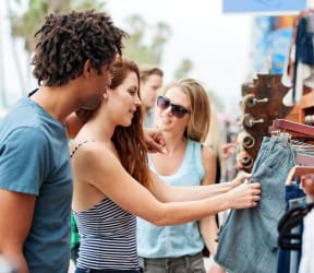 people looking at a pair of jeans at an outdoor market