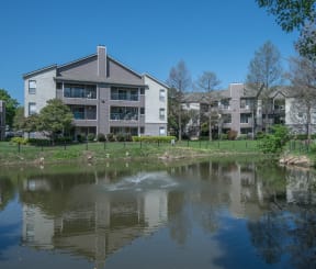 an apartment building overlooks a lake in front of a fountain