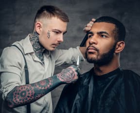 a man with a tattoo on his arm is having his hair cut by a hairdress