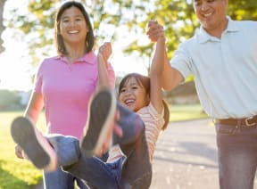 a family walking down a path with a child jumping in the air