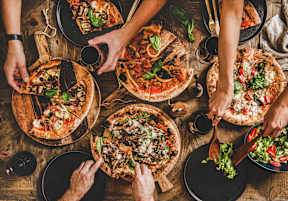 A group of people enjoying a variety of pizzas together.