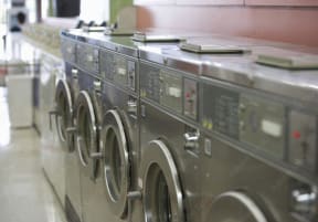 a row of industrial washing machines in a public laundromat at Clinton Towers, Bronx, NY, 10457