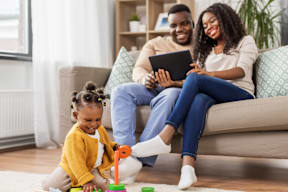 a young girl playing with toys with her parents on the couch