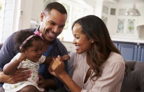 a man and woman sitting on a couch with a baby