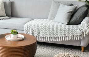 a living room with a couch and a coffee table with a blanket on it