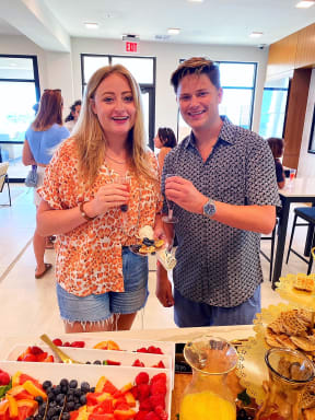 a man and a woman standing in front of a table of food