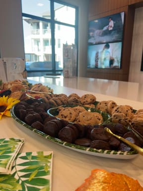a large platter of cookies and muffins on a table with a television in the background