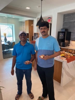two men standing in a kitchen holding sandwiches