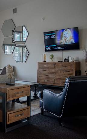 A living room with a grey sofa, a wooden table, and a television on the wall at Arrowhead Ridge Apartments, Rio Rancho, NM, 87124