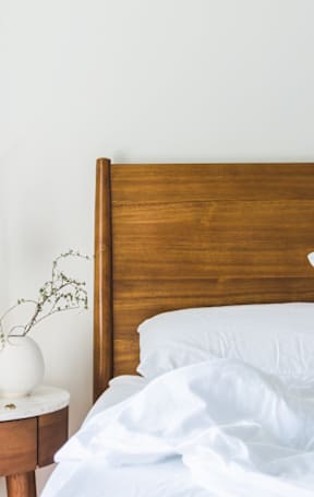 A bed with white pillows and a wooden headboard is in the image.