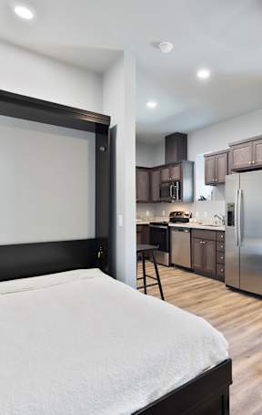 A white washing machine is in a small alcove in a room at ONE18 West Street Residential Apartments, Reno, 89501