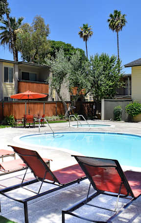 A pool with chairs and a red umbrella.
