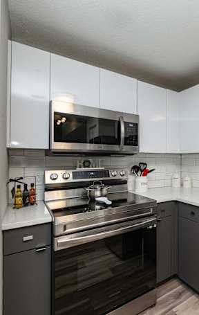 A modern kitchen with a stainless steel refrigerator and black appliances.