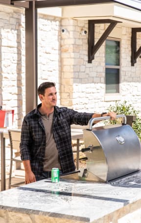 a man standing in front of a grill in a backyard