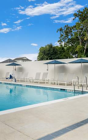 A large swimming pool with lounge chairs and umbrellas.