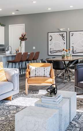 A modern living room with a grey sofa and a dining table set up.