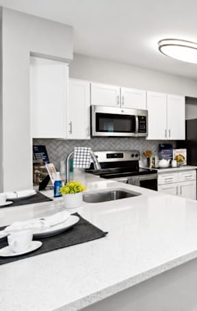 A modern kitchen with white countertops and stainless steel appliances.