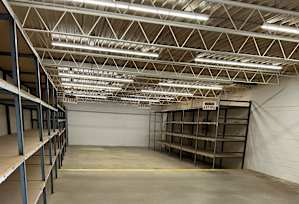 A large empty warehouse with metal shelving and a concrete floor.