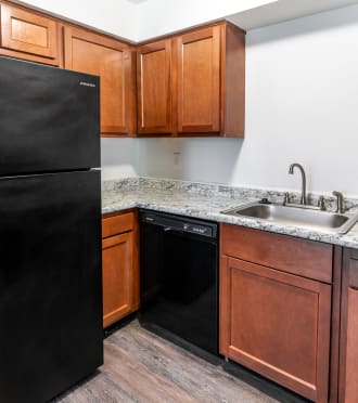 a kitchen with a black refrigerator and wooden cabinets