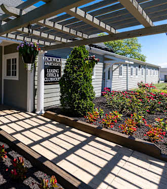 a porch with a pergola in front of a white building with a sign at Pickwick Farms Apartments, Indianapolis, IN