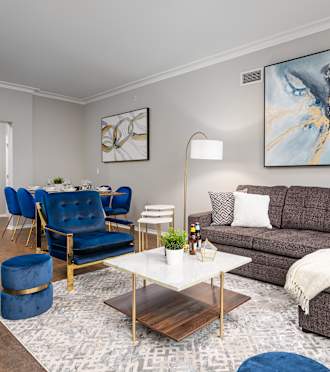 A living room with a grey sofa, a blue chair, and a painting on the wall at Park Heights by the Lake Apartments, Illinois, 60649.