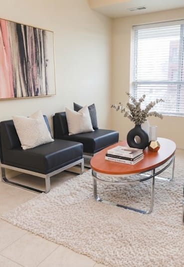 A living room with a black couch, a coffee table, and a painting on the wall.