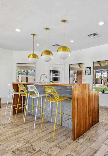 A modern game room at Sentry Apartments offers foosball, pool, and shuffleboard tables, with large windows overlooking the pool.