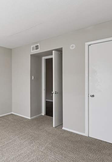 A room with a carpeted floor and two doors.