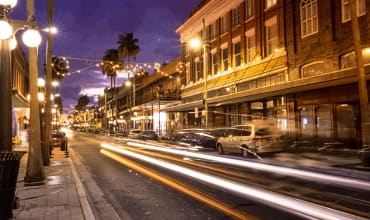 a city street at night with cars driving down it