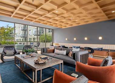 A modern living room with a wooden ceiling and a large window.