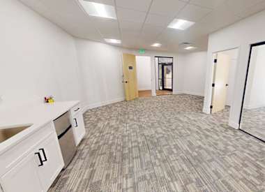 A spacious office room with a carpeted floor and white walls.