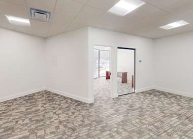 A room with a carpeted floor and a door on the right side.