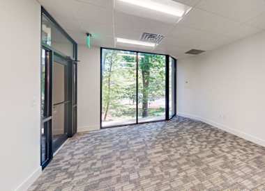 A room with a carpeted floor and a glass door leading outside.