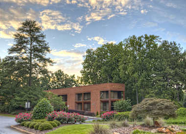 A building with the word "AVILA" on it is surrounded by trees and flowers.