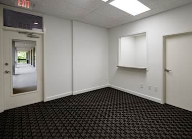 A room with a black carpet and white walls with a door on the left.