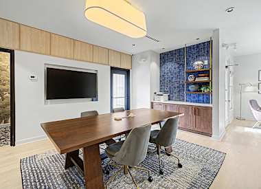 A modern dining room with a wooden table and grey chairs.